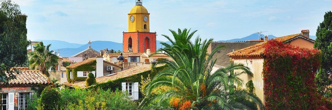 A bright orange building sticks out atop rooftops and palm trees.