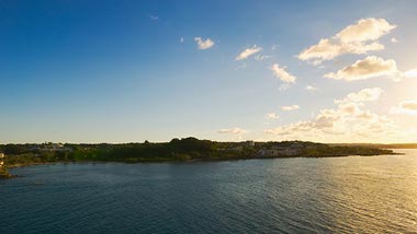 A serene sunset over calm water and land in the distance.