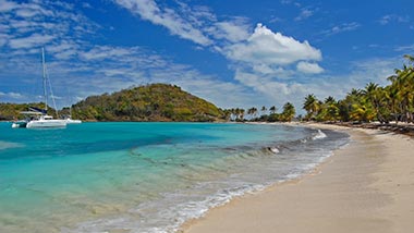 A serene beach view of fresh sand and bright blue water washing up on shore.