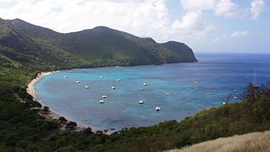 A bright blue bay leading to green mountains.