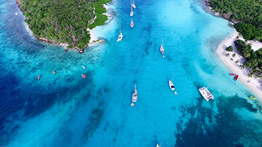 Aqua sea dotted with boats meets white sandy beaches and lush greenery.