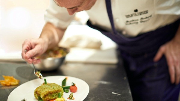 A chef adds garnish to a dish.