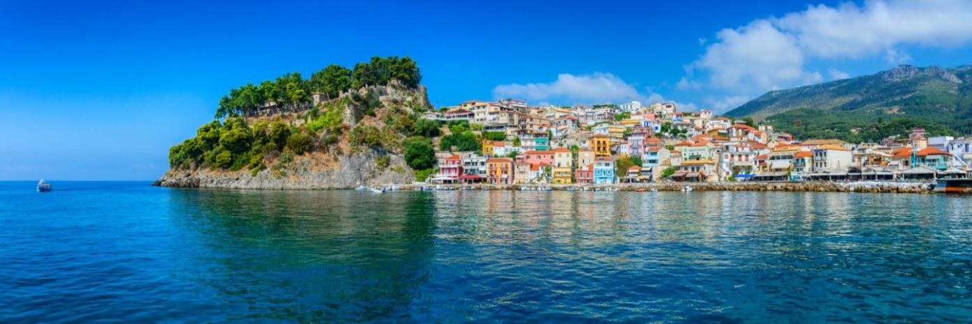 A town sits right on the rocky edge of the blue water.