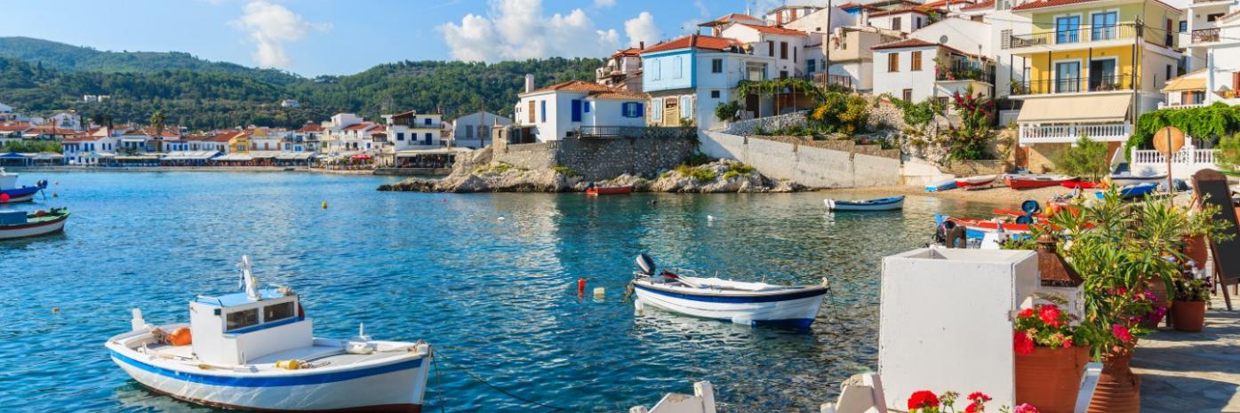 Boats sit anchored in blue water before a seaside town.