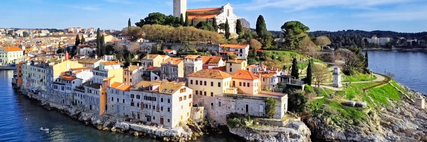 A town sits right on the rocky edge of the blue water.