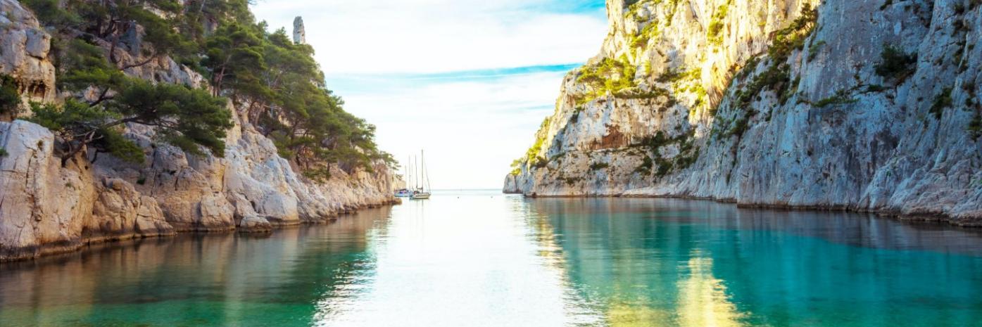 Two large cliffs break for blue water to run up to a sandy shore.