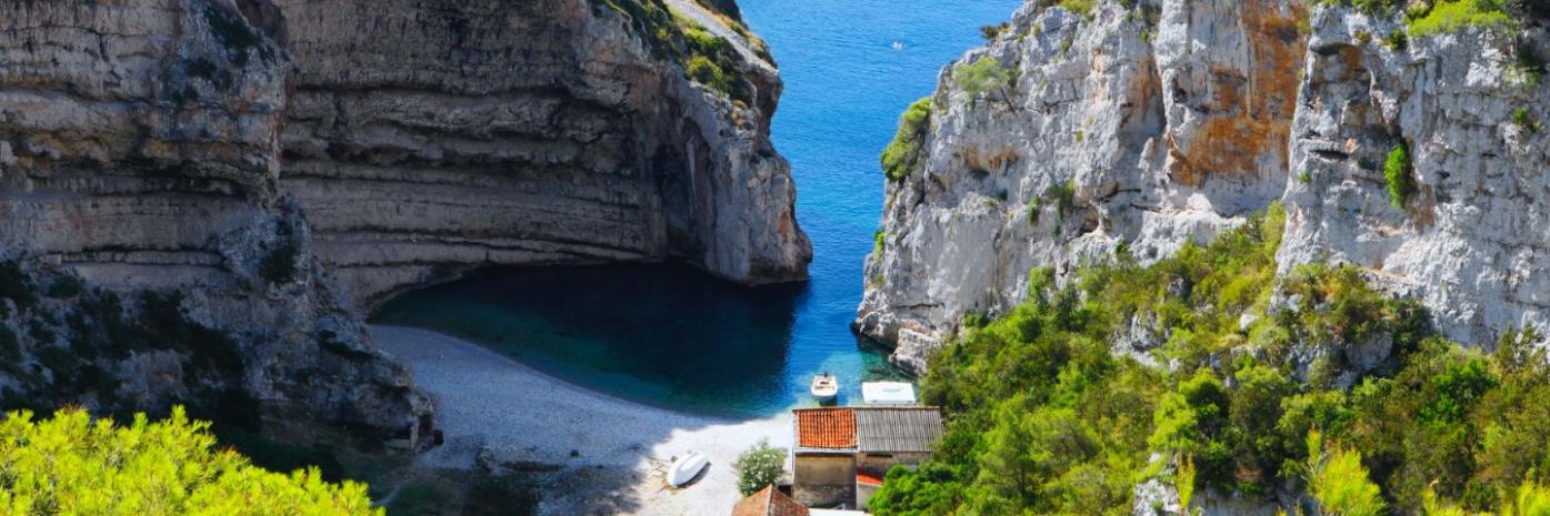Two large cliffs break for blue water to run up to a sandy shore.