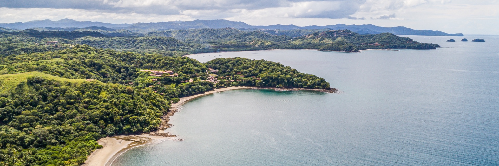 An aerial view of a long stretch of beach and bright blue water.