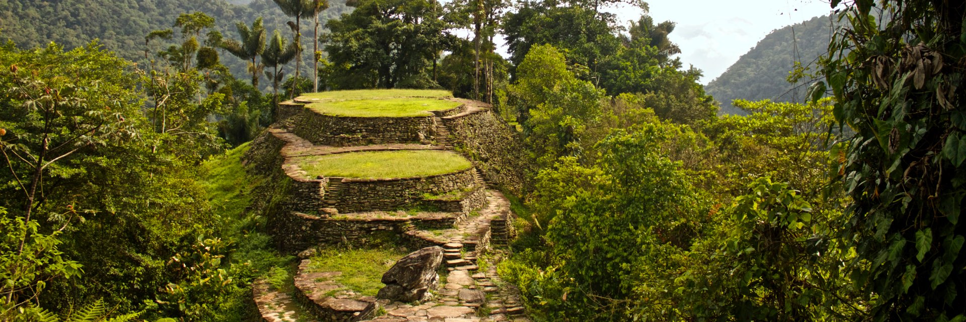 Steps to ruins in a mountainous region surrounded by green landscape.
