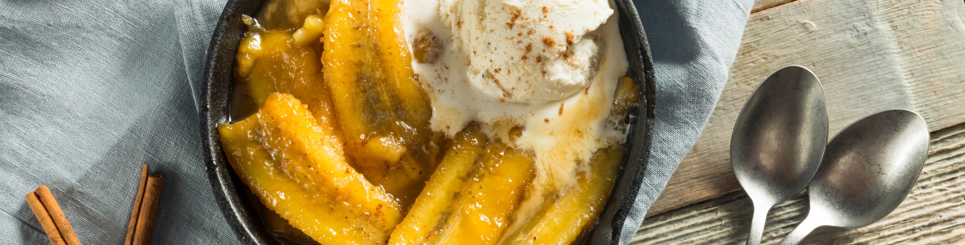 A small cast iron skillet with caramelized bananas and vanilla ice cream.