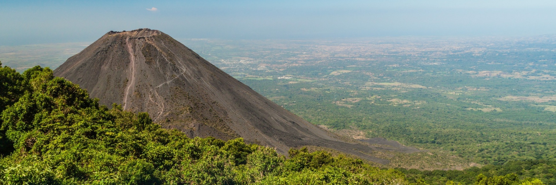 Lush greenery surrounds a volcano.