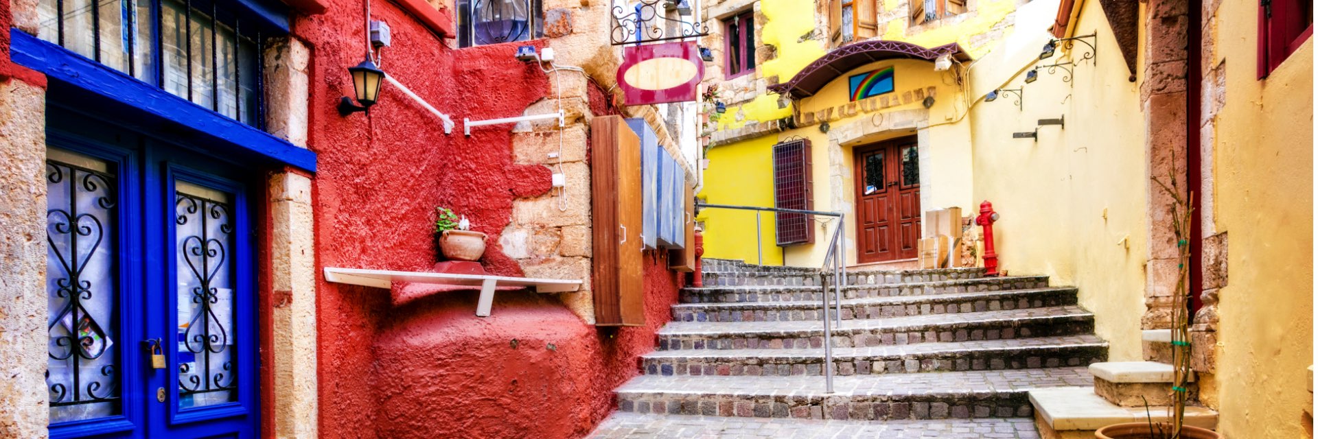 A stone walking path stairway with brightly colored buildings on each side in Chania, Crete