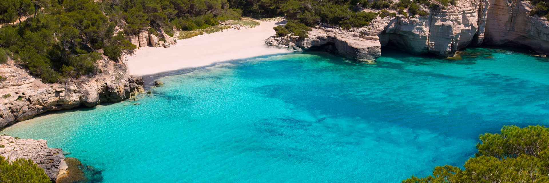 White sandy beach with coral cliffs and aquamarine waters.