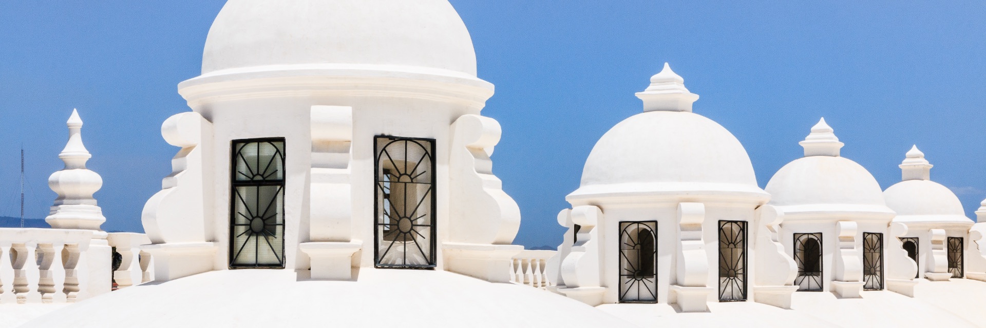 White rounded structures with black windows in front of clear blue sky.