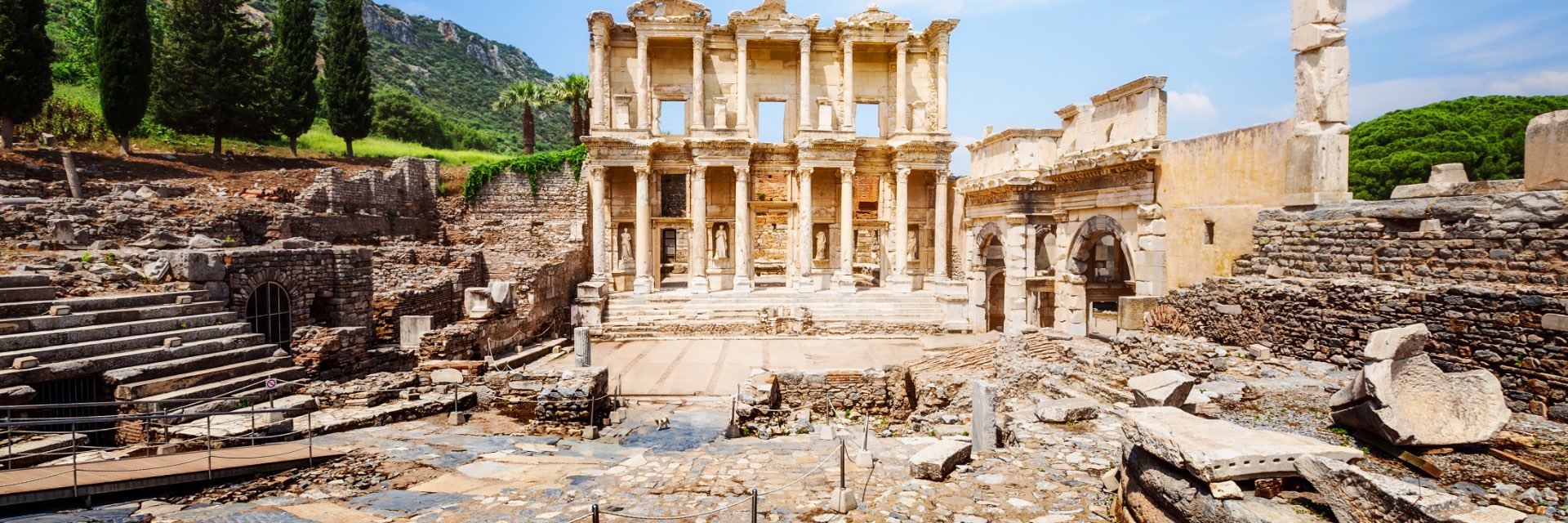 Ancient Roman ruins surrounded by lush green background with Cypress trees.