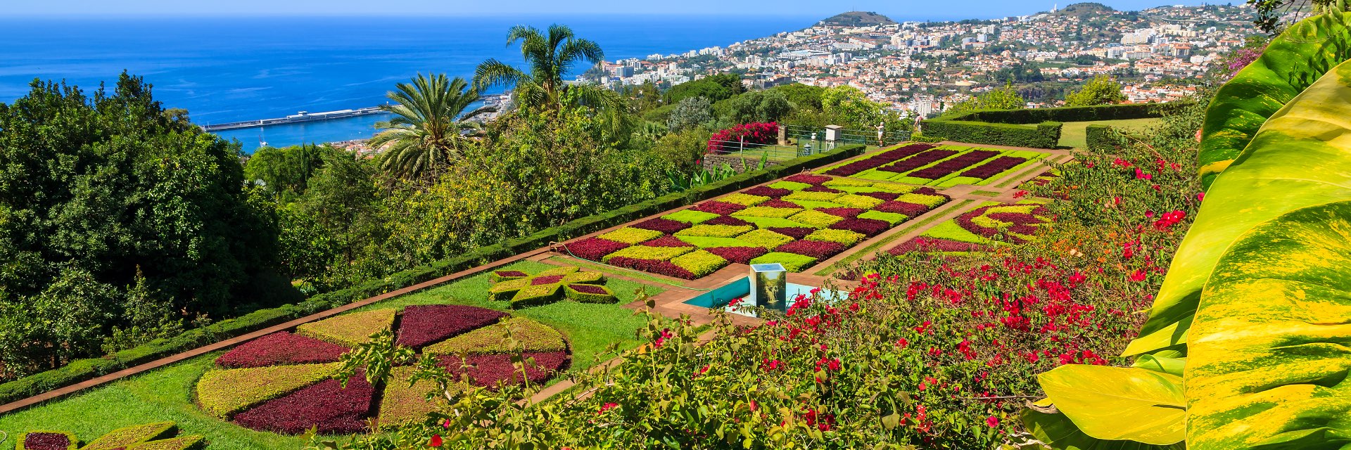 Aerial view of checkered pattern landscaping with town and sea in background.