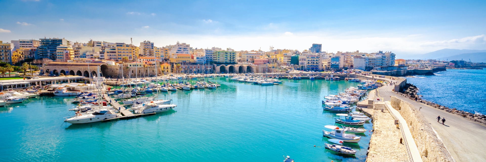 Bright blue water in a marina filled with boats along a vibrant seaside town.