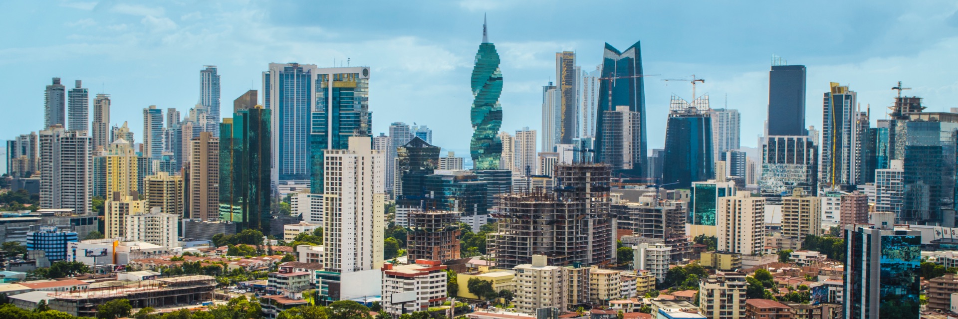 Tall buildings and skyscrapers create the city skyline against the bright blue sky.