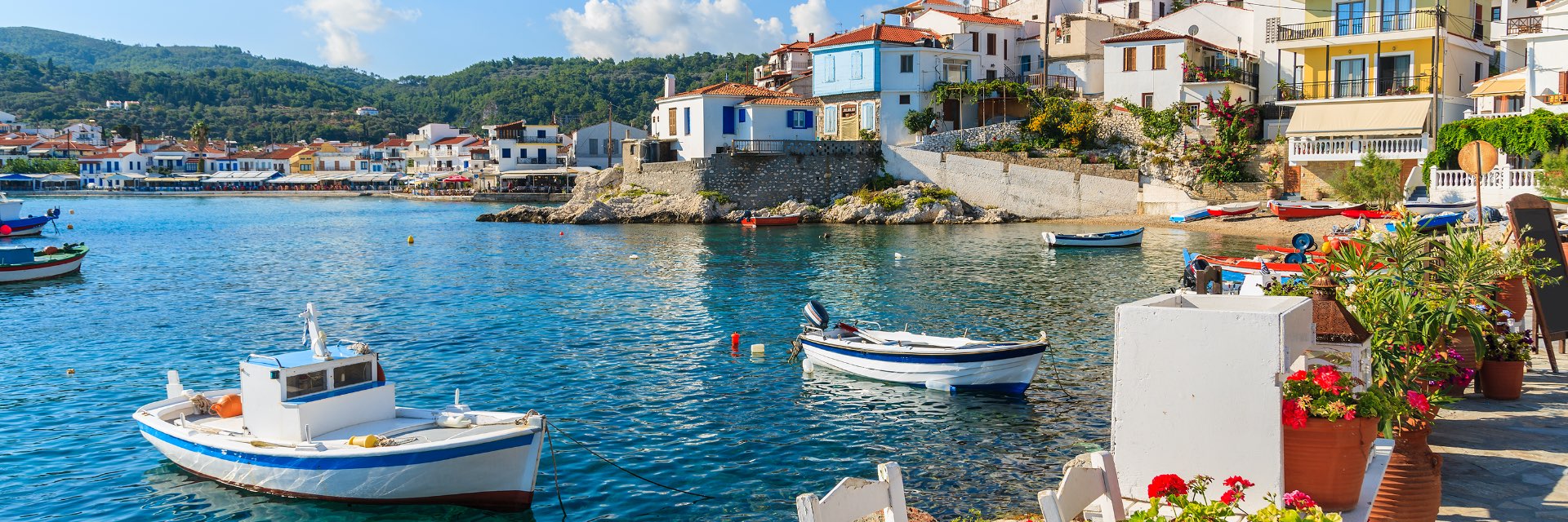 Boats sit anchored in blue water before a seaside town.