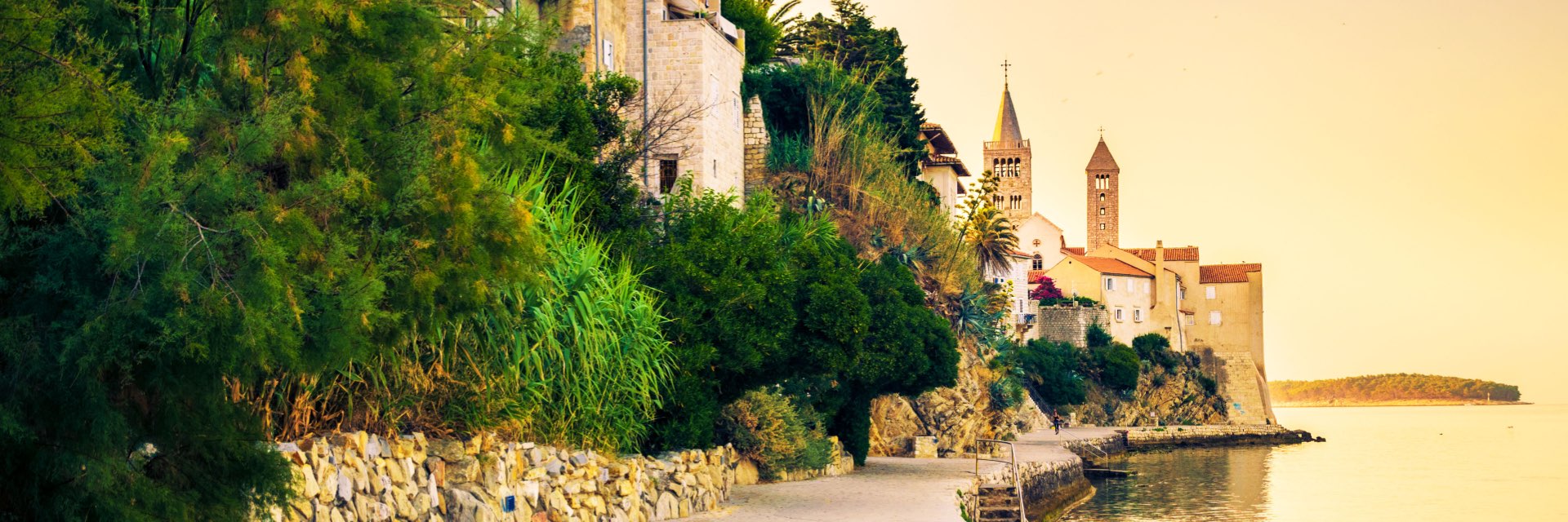 View of Croatian town from walkway along the coast during sunset.