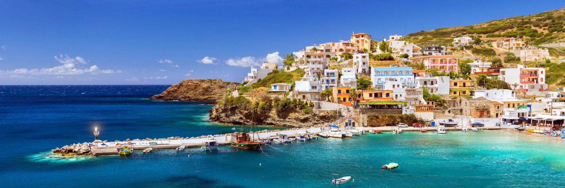 Bright blue water reaches up to the shore, where houses are lined along the hill.