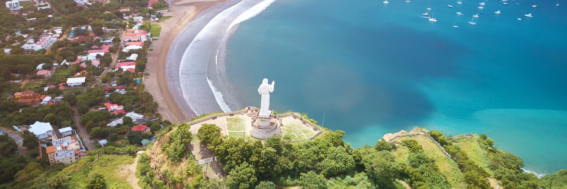 An aerial view of vibrant blue water and waves crashing onto the beach in front of town.