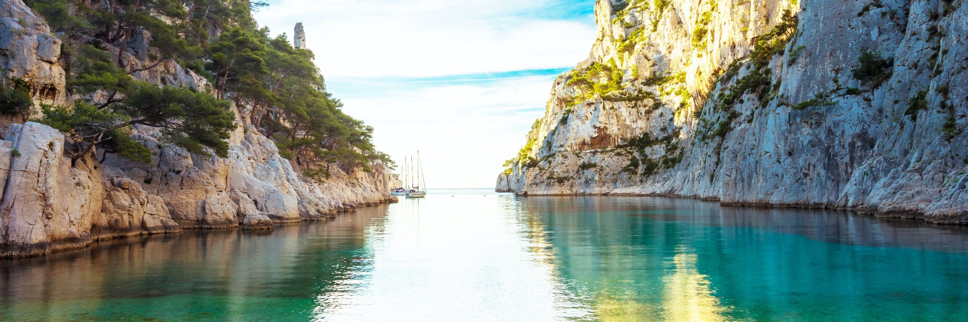 Calm water before a rocky shore between two mountains.