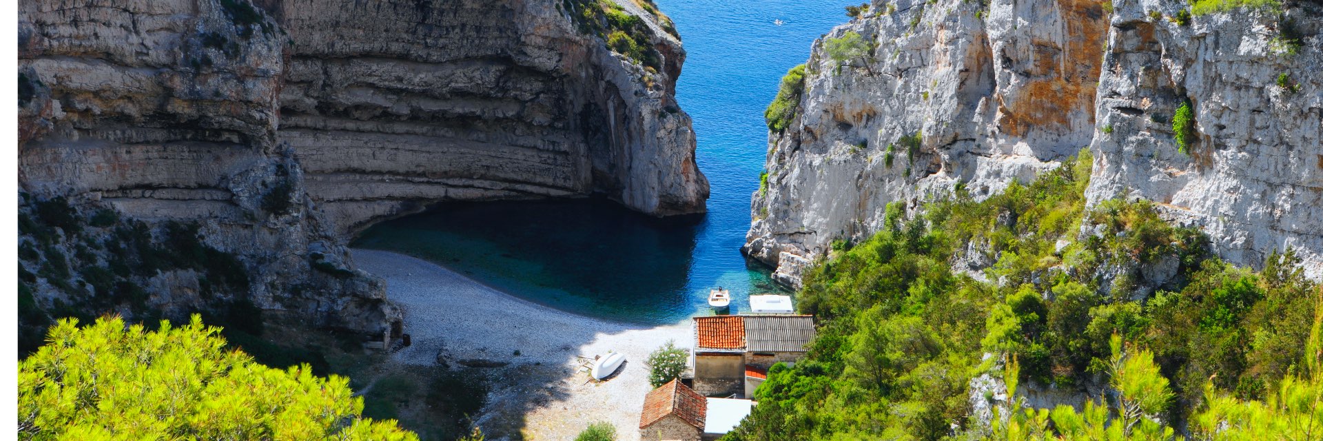 Two large cliffs break for blue water to run up to a sandy shore.