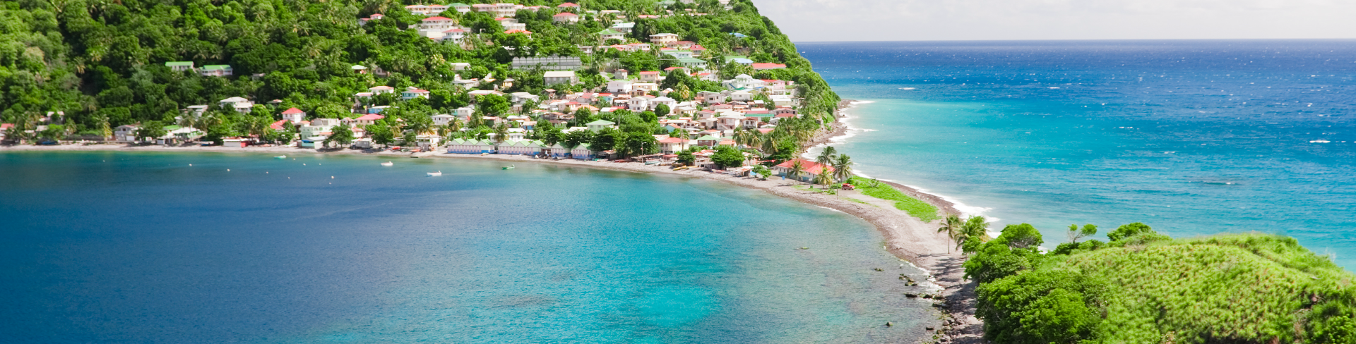 A strip of land that connects two large green hills and overlooks the sea.