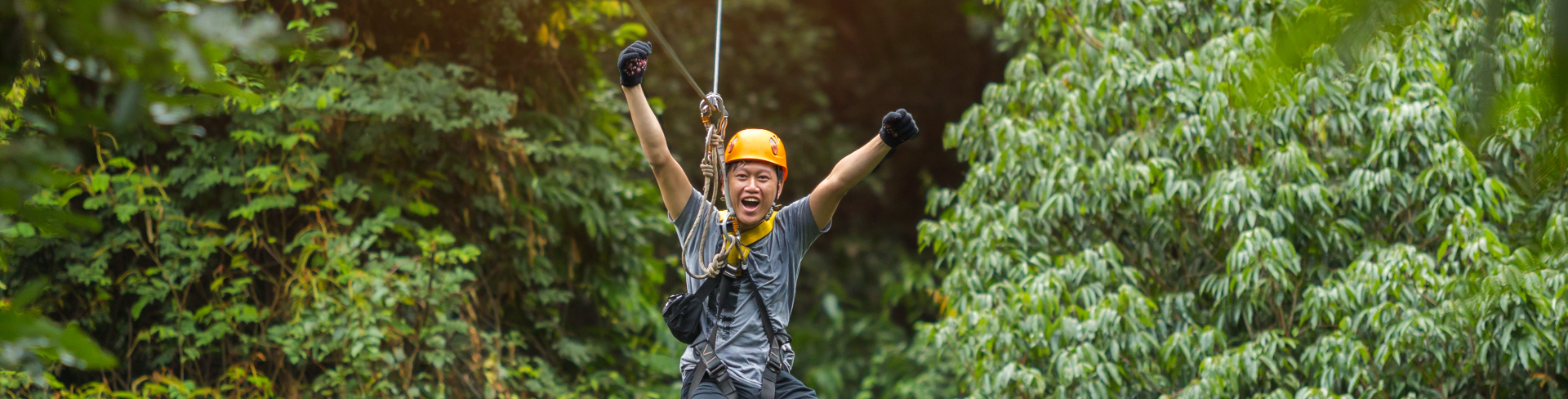 A person zip lining through a rain forest.