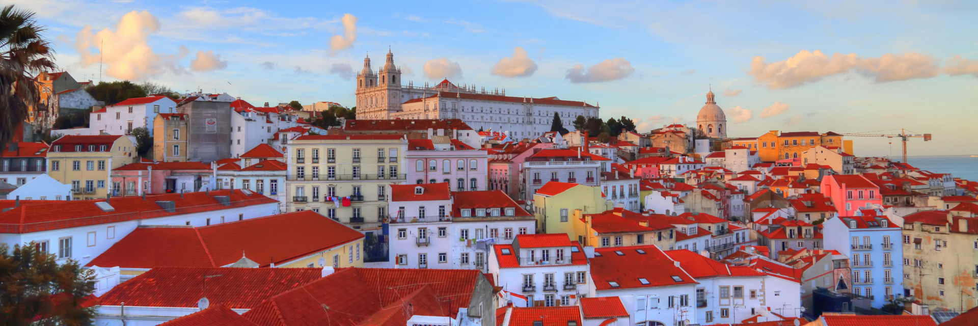 Red roofed houses in a hillside town under a sky of bright clouds.