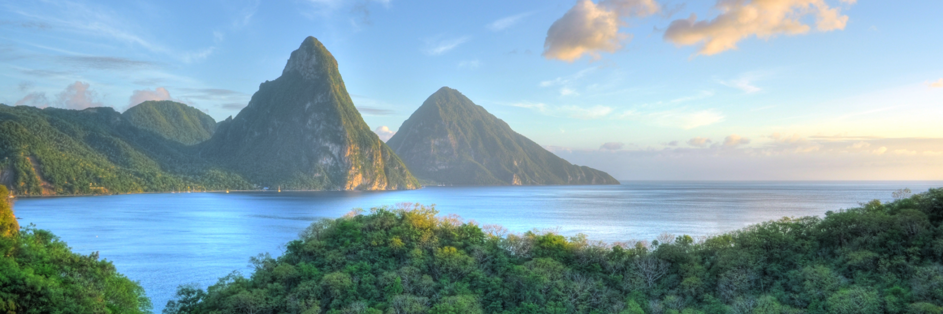 A misty view of green mountains over bright blue water.