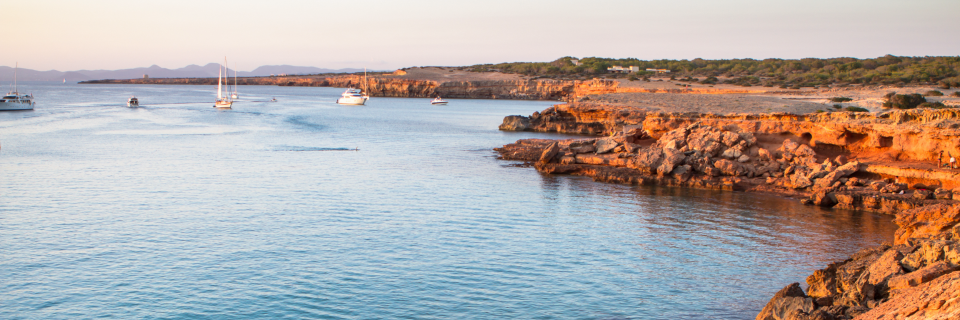 Orange cliffs along a ragged shoreline overlook the water.
