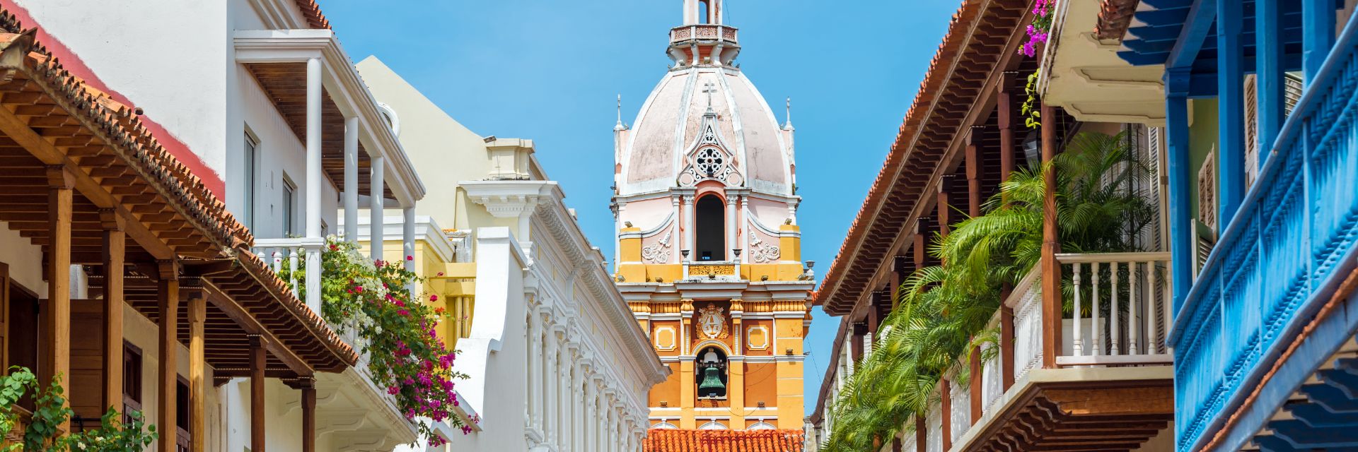 The view of balconies of Spanish-style buildings leading to a view of a cathedral.
