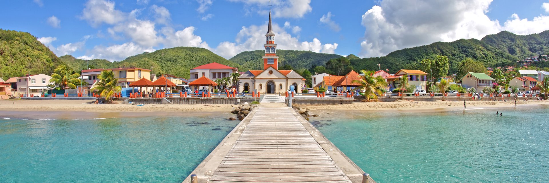 Wooden Pier with church and small village along seaside.