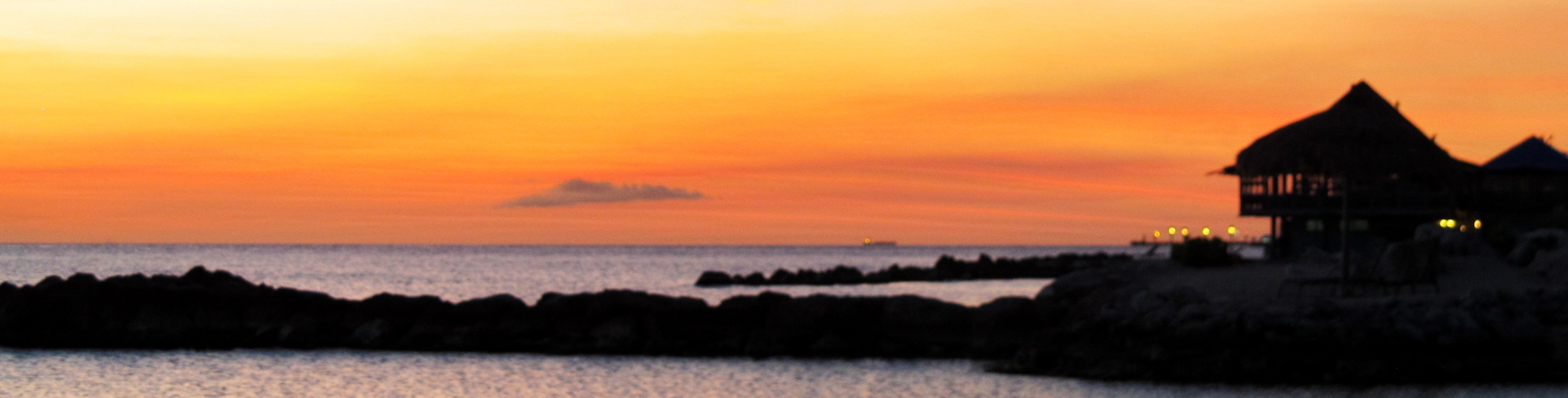 A stilt house by the sea at sunset.