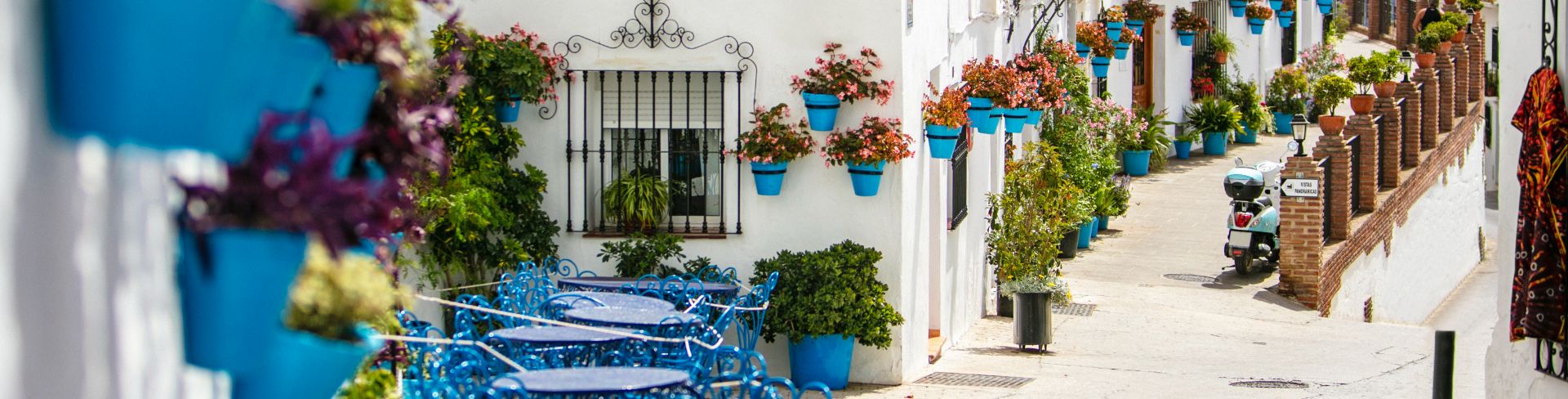 A street in Mijas with white houses decorated with blue flower pots.