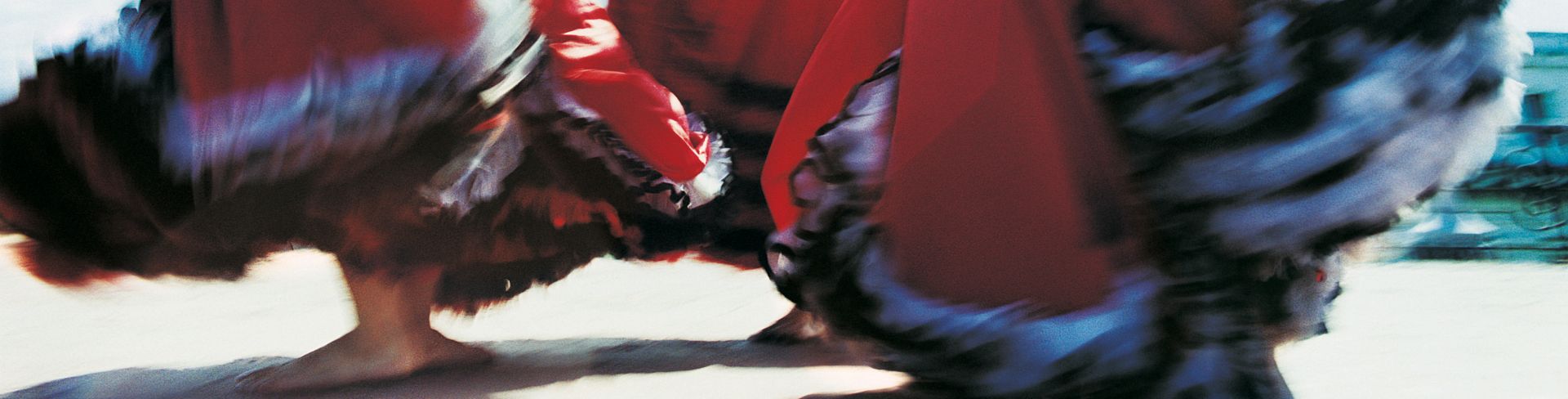 Three women dancing flamenco in traditional skirts.