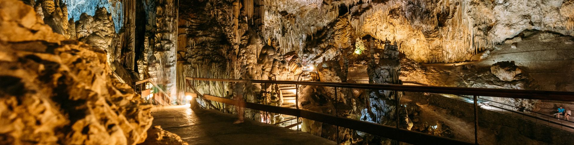 A natural cavern lit up to see the stalactites hanging from the roof of the cave.