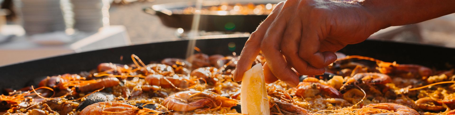 A large pan filled with paella, featuring mussels, prawns and rice.