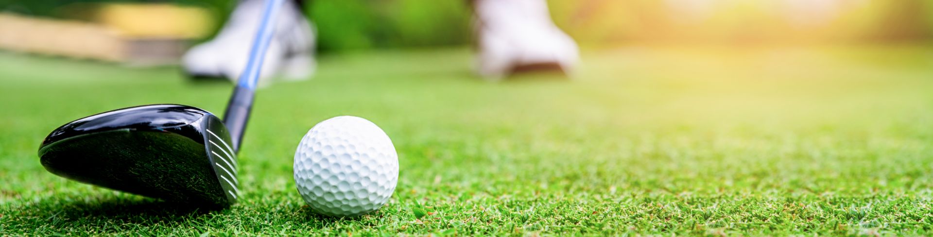 Close-up shot of a golfer's feet, club and ball setting up a shot.