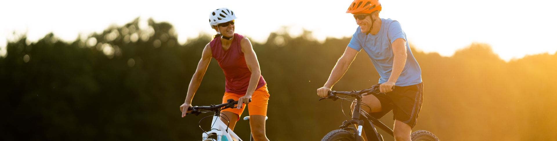 Two people riding bikes through a grassy field.