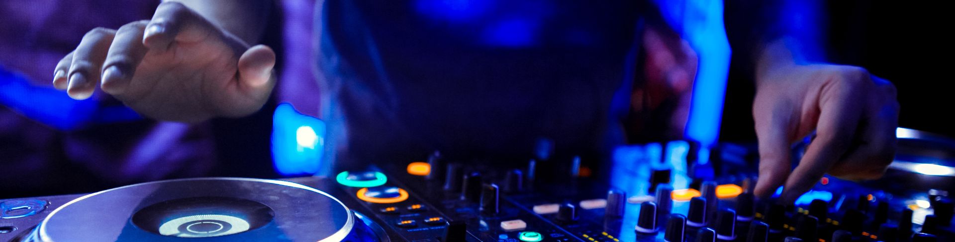 A person standing at a DJ turntable, mixing music.