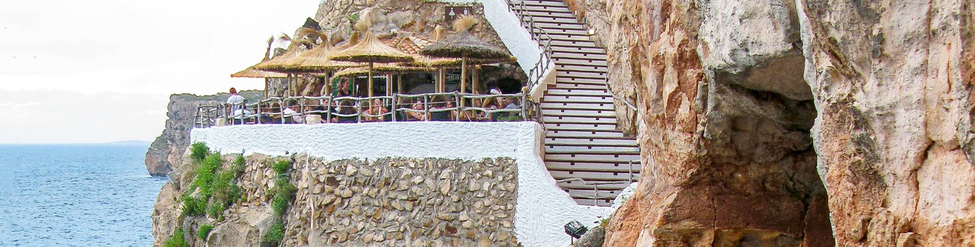A restaurant built into a cliff overlooks the ocean.