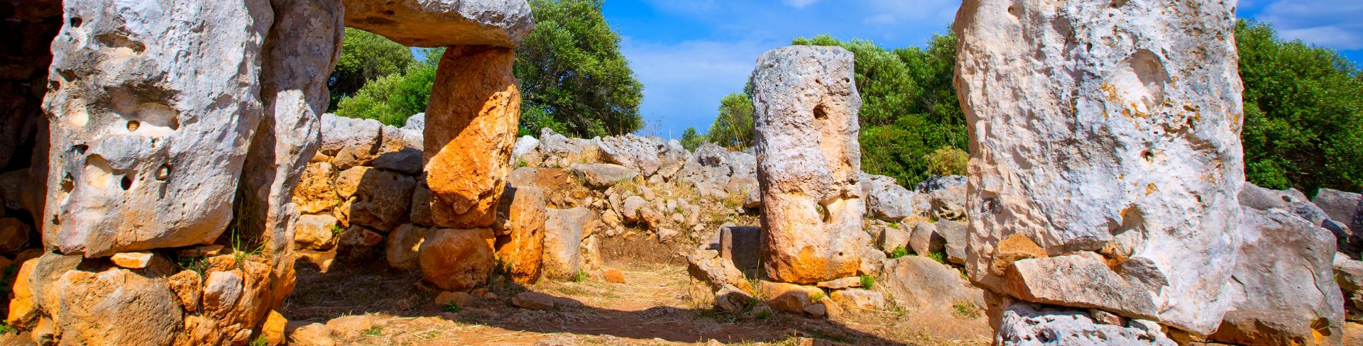 Ancient stone monoliths stand in a small area fenced in by a stone wall.