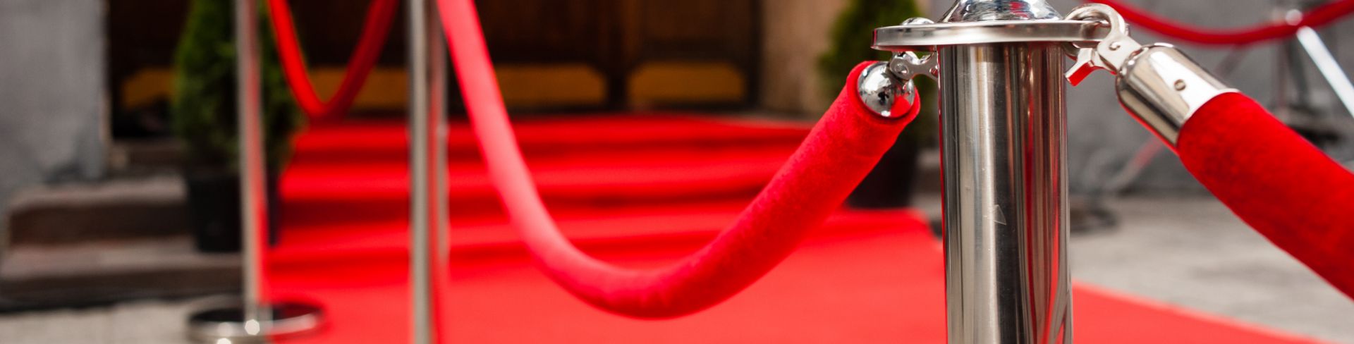 A red carpet on a walkway, roped off by red velvet ropes.