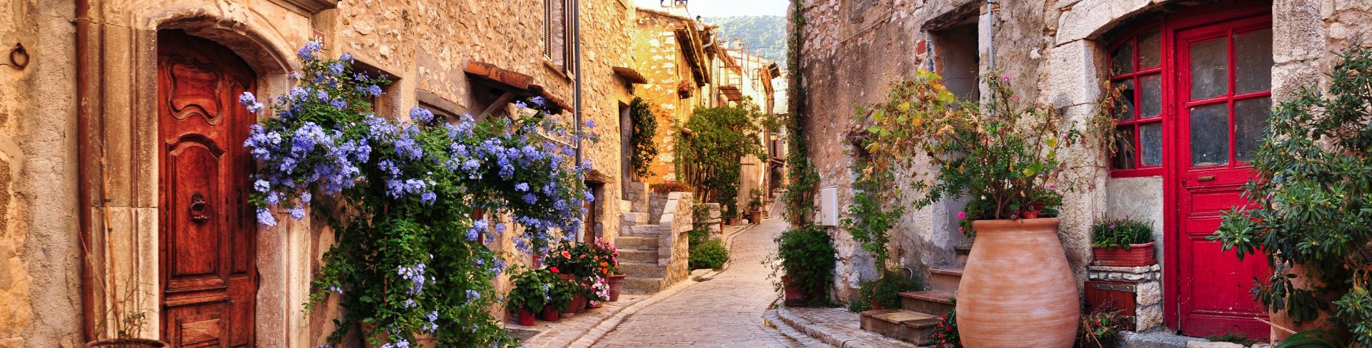 A look down a pedestrian stone street surrounded by old French village houses.
