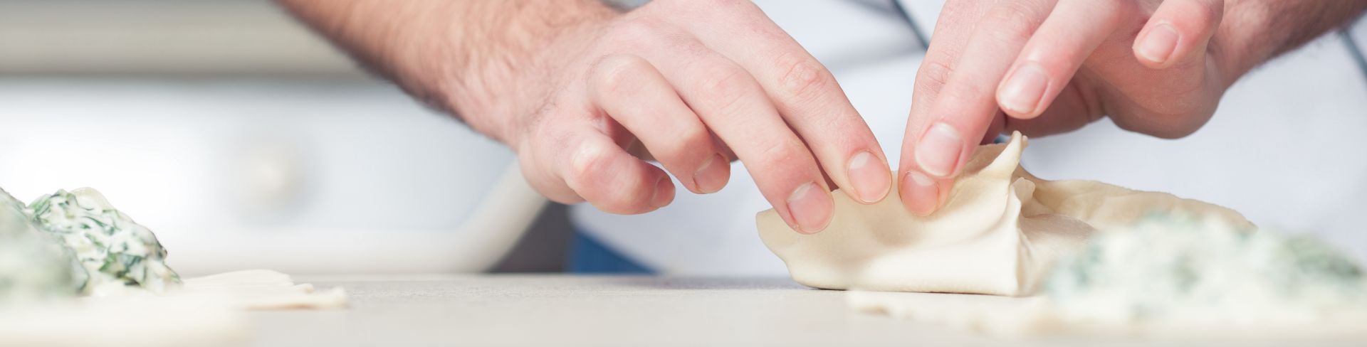 A chef delicately folds pastry dough around a spinach filling.