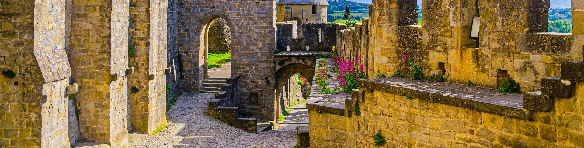  A walled city featuring stone ramparts, turrets and stairs.