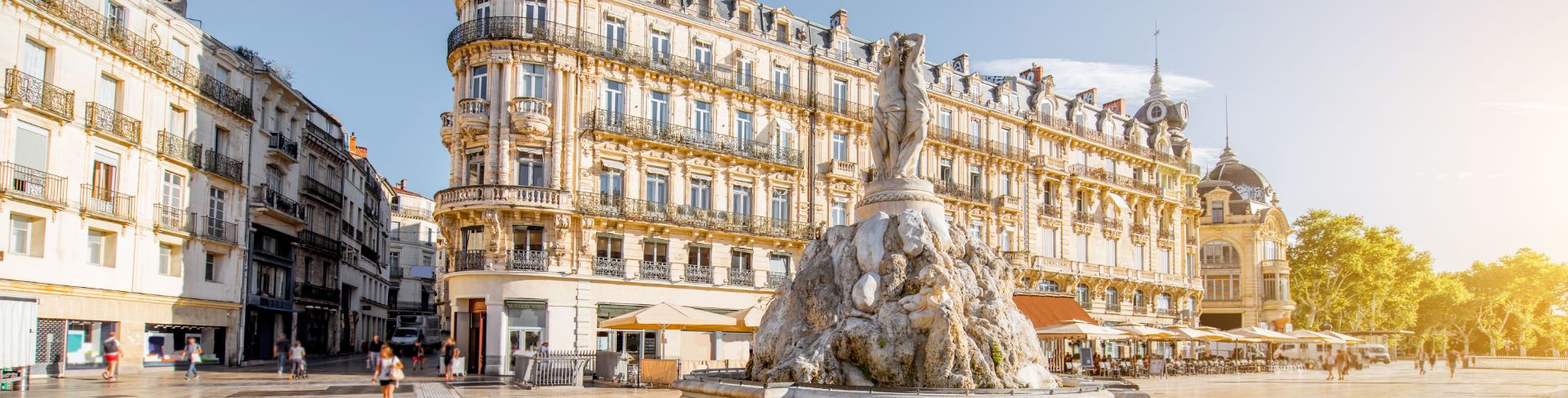 A square in France featuring a bubbling fountain and 19th-century buildings in the background.
